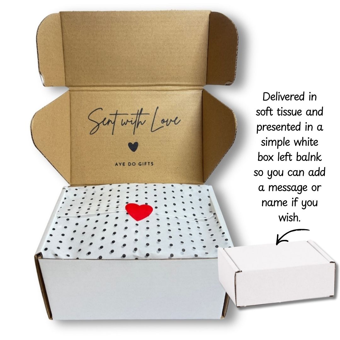 An open cardboard gift box from Aye Do Gifts with a white tissue paper lid printed with black polka dots and a small red heart. Text on the right explains the packaging, and a small closed white box is shown at the lower right.