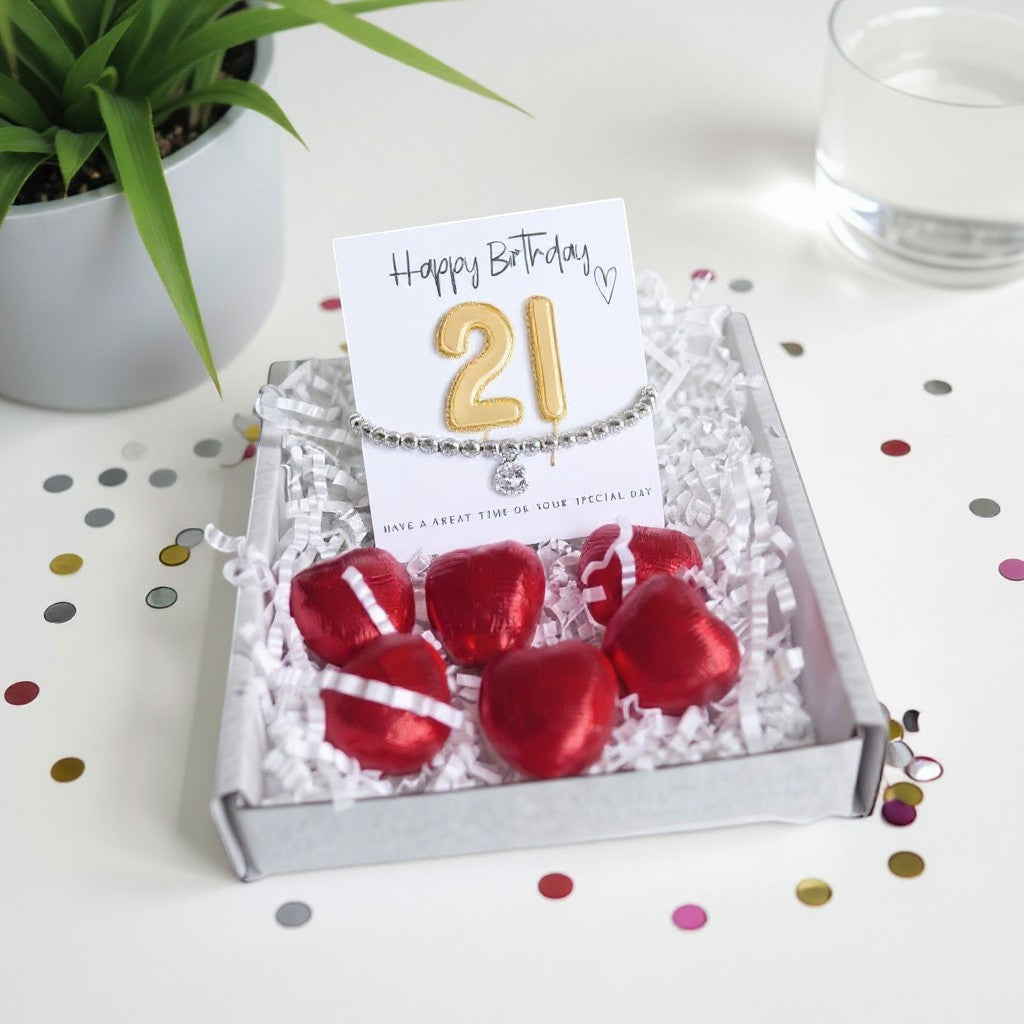AyeDoGifts 21st birthday gift hamper with silver beaded bracelet, cubic zirconia charm, gold '21' balloons and red chocolate hearts.
