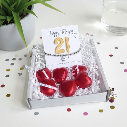 AyeDoGifts 21st birthday gift hamper with silver beaded bracelet, cubic zirconia charm, gold '21' balloons and red chocolate hearts.