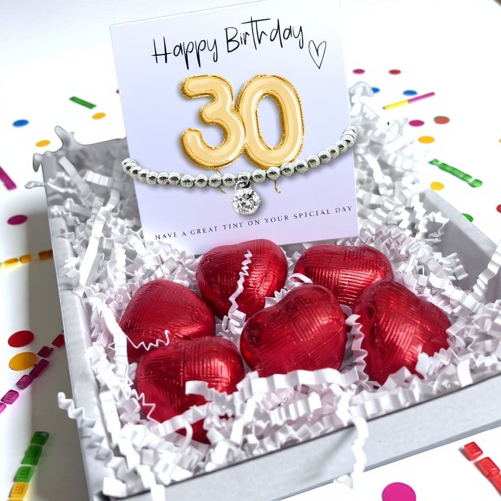 AyeDoGifts 30th birthday gift hamper with a silver beaded bracelet featuring a cubic zirconia charm and a gold '30' balloon card, plus red chocolate hearts.