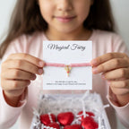 AyeDoGifts pink nylon friendship bracelet with gold enamel fairy charm, presented with red foil heart chocolates.